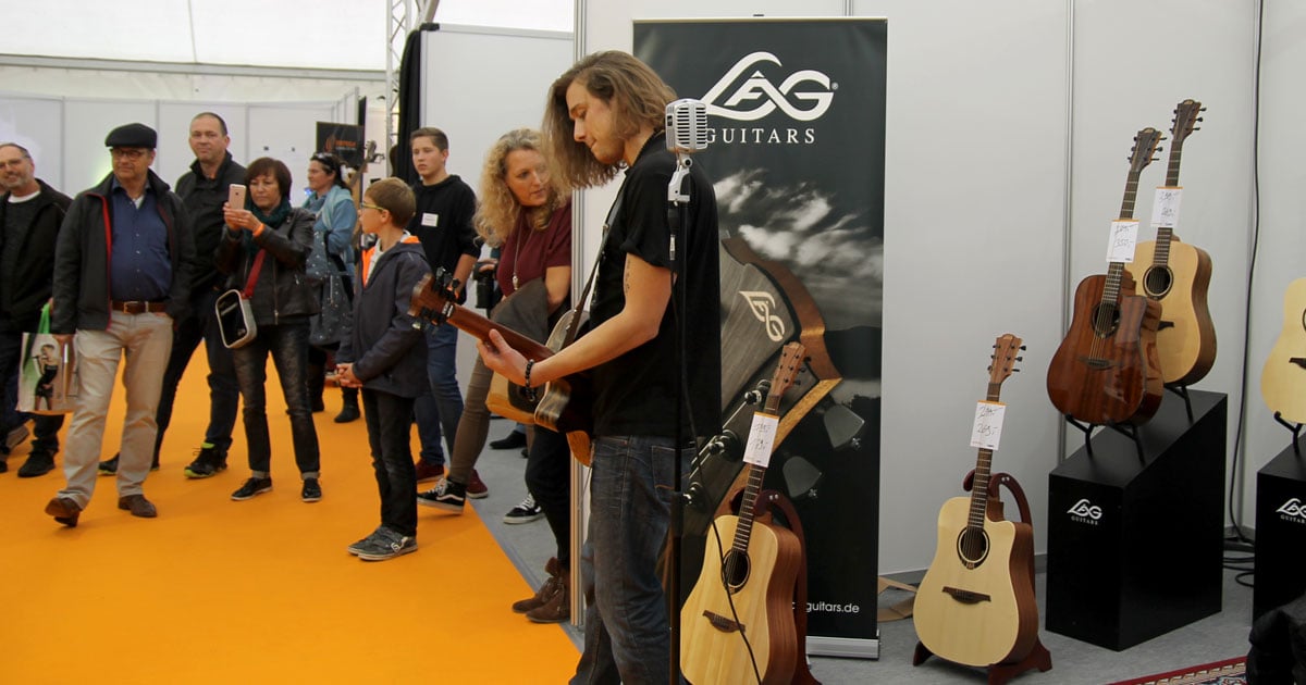 Sebastian Dracu am Stand von Lag Guitars im Messezelt