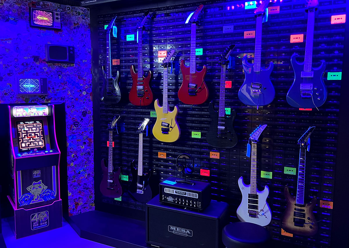 Kramer-Gitarren im mit Blaulicht beschienenem Raum in der Gibson Garage London. Neben den Gitarren ein alter Spielautomat.
