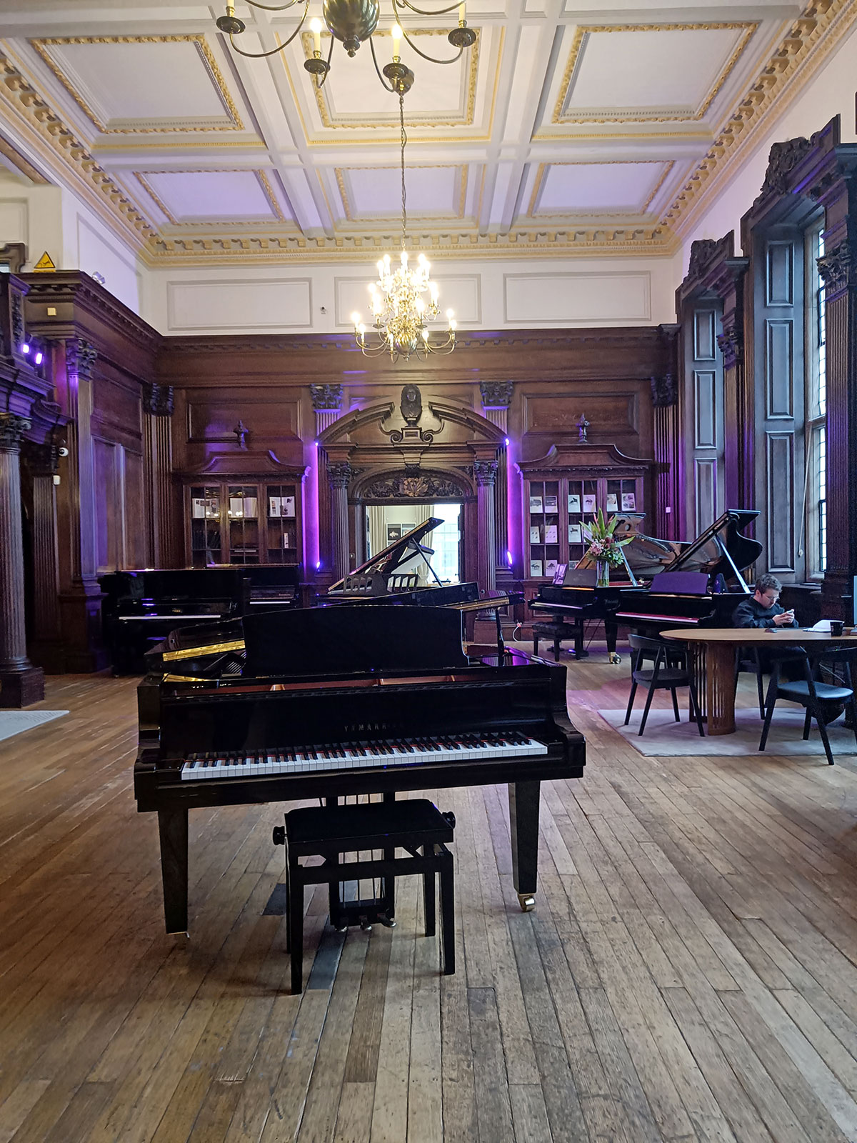 Raum mit hohen barocken Decken und Holzfußboden im Yamaha-Store London. Darin diverse Klaviere und Flügel.