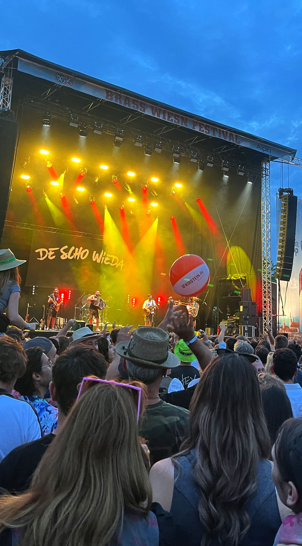 Während eine Band auf der Bühne spielt, wird im Publikum ein Kirstein-Wasserball in die Luft geworfen.