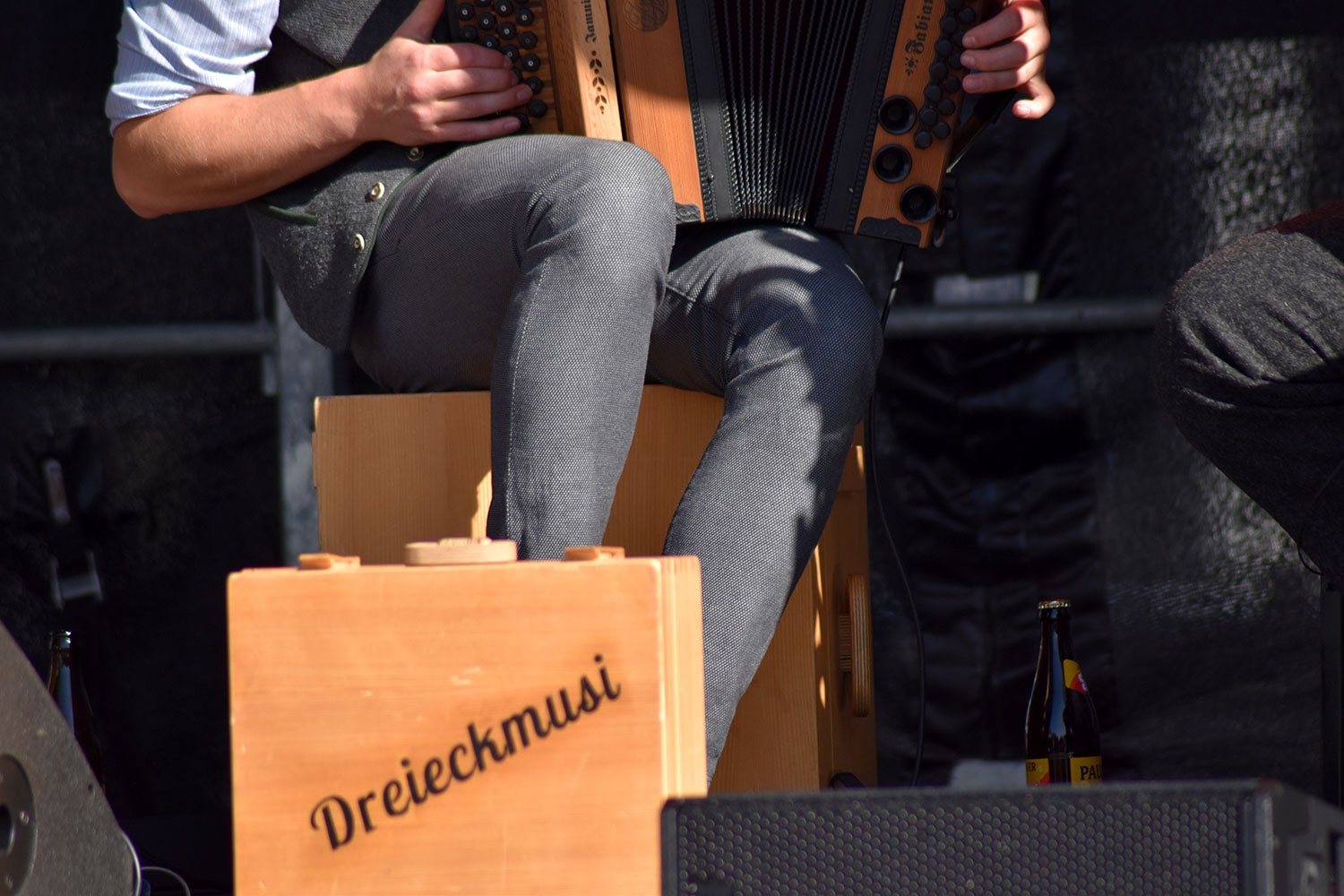 Detailbild des Auftritts der Dreieckmusi bei der MusiConnect 2024. Im Vordergrund ein Holzkoffer mit Schriftzug der Band.