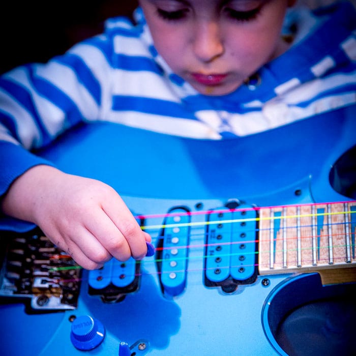 Junge beim konzentrierten E-Gitarre spielen